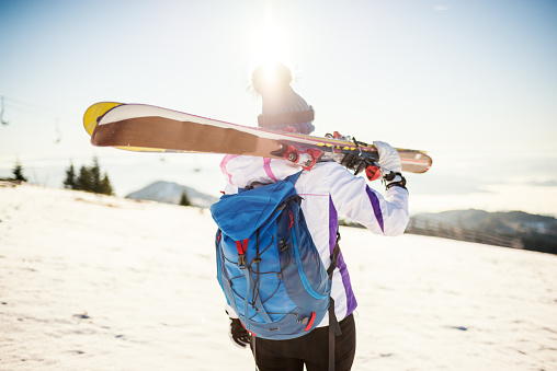 Young woman after skiing on sunny day with backpack  and 