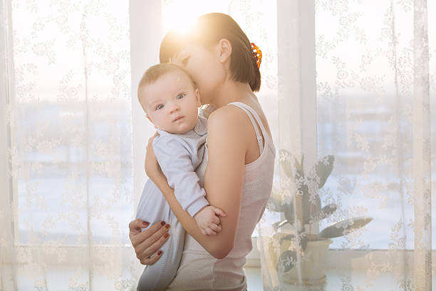 istock Loving mother playing with her baby sitting on a window 503633486