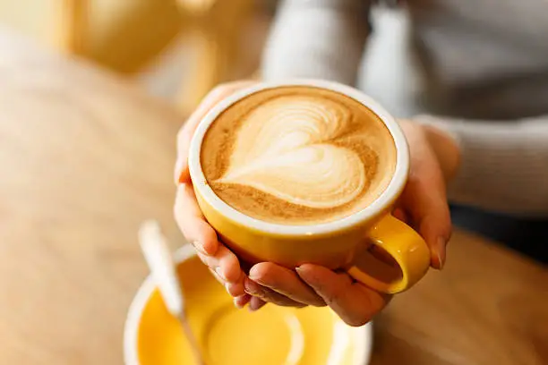 Photo of lady's hands holding cup with sth heart-shaped