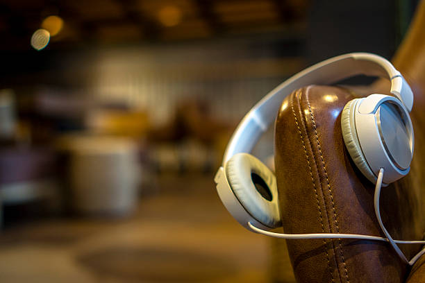 passant pour écouteurs sur le bras de canapé en cuir dans un café - armchair comfortable relaxation headphones photos et images de collection