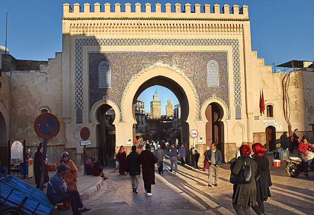 Gateway to Morocco Fes, Morocco - December 1st 2015: Moroccan people come and go through the historic Blue Gate (Bab Bou Jeloud) which is one (and most famous) of the ancient portals to the Medina (old city). Evening sunlight casts strong shadows. bab boujeloud stock pictures, royalty-free photos & images