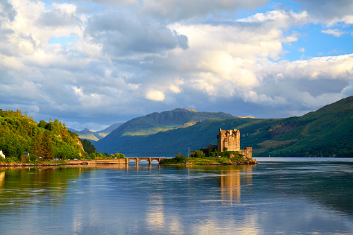 Dornie, Scotland - August 3, 2015: Afternoon sunlight falls upon the iconic form of Eileen Donan Castle in Scotland. The waters of Loch Alsh, Loch Duich and Loch Long meet close to the tidal island upon which the castle sits.