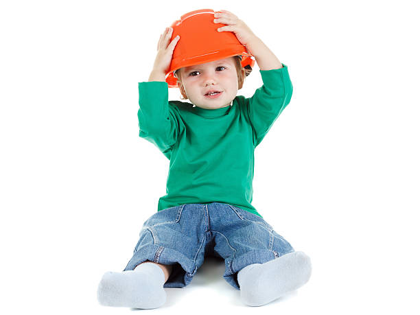 istock Little child plays with orange construction protective helmet  on white 503656914