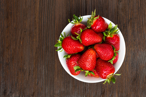 Fresh ripe strawberries in a simple white bowl