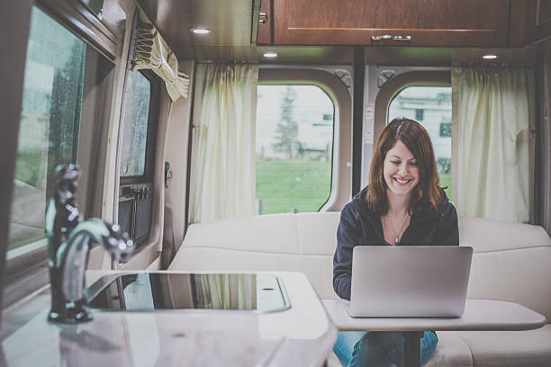 jeune femme à l'aide d'ordinateur portable à l'intérieur de camping-car - motor home park camping luxury photos et images de collection