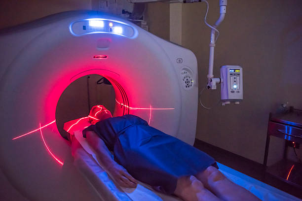 Patient lying under a CT scanner in hospital Person undergoing a CAT scan in hospital. PET scan equipment. Medical scan of patient. pet scan photos stock pictures, royalty-free photos & images