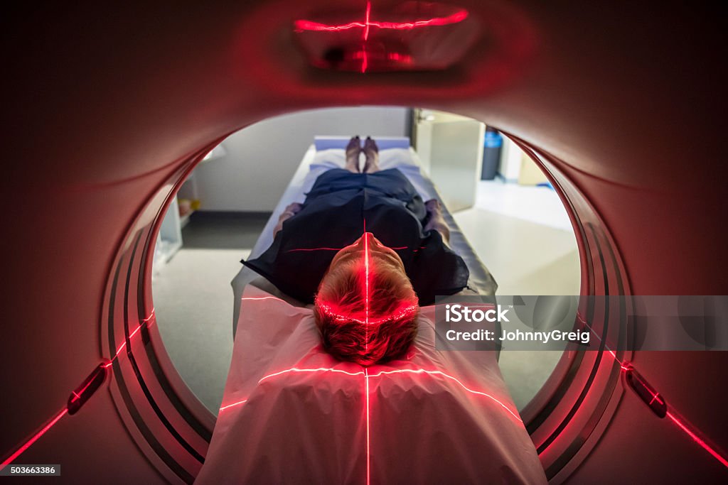 Patient lying inside a medical scanner in hospital Person undergoing a CAT scan in hospital. PET scan equipment. Medical CT scan of patient. MRI Scan Stock Photo