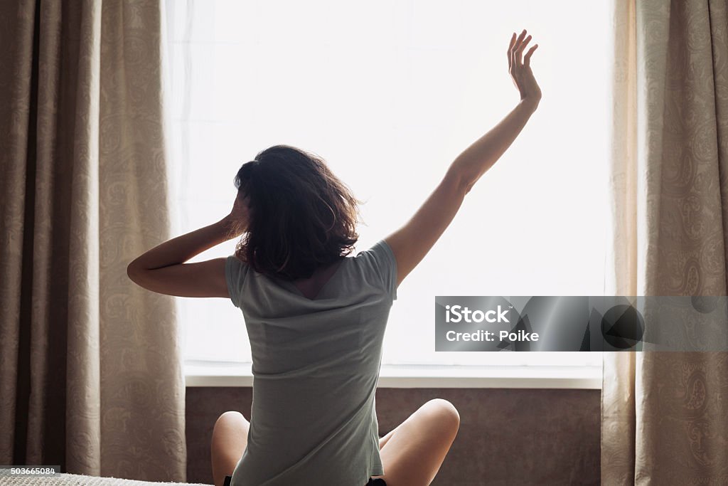 Mujer joven de estiramiento en la cama - Foto de stock de 20 a 29 años libre de derechos