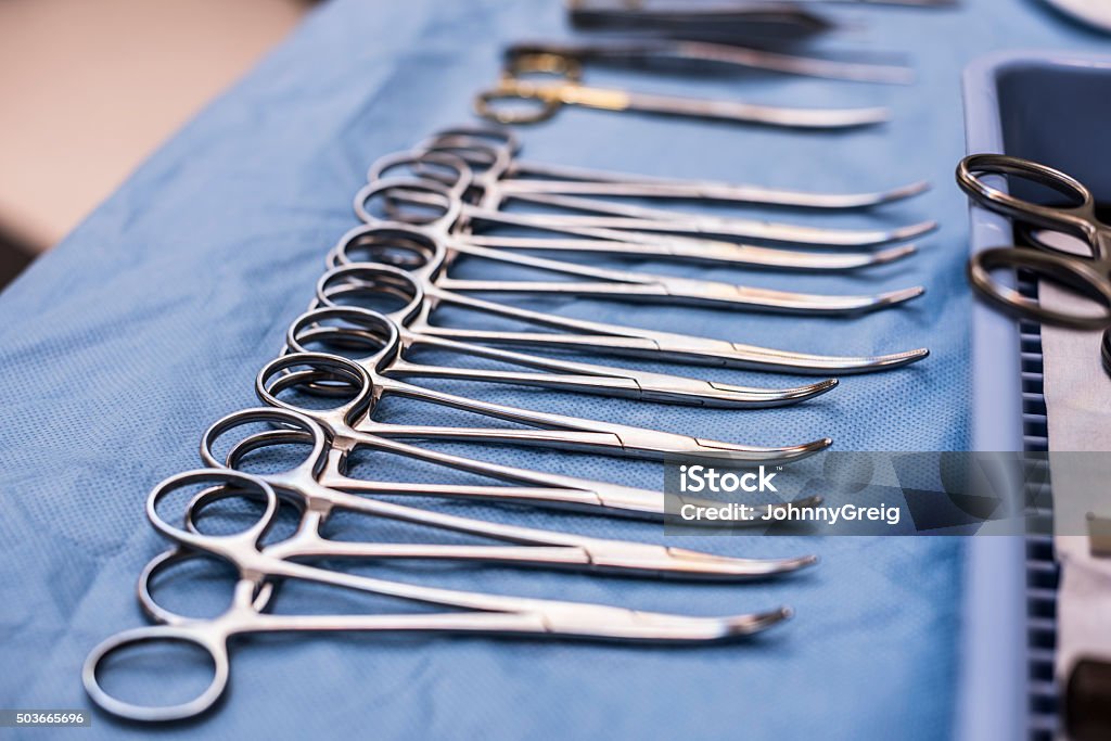 Surgical scissors lined up on blue cloth in operating theatre Collection of medical scissors used during surgical operations in a row. Accuracy Stock Photo