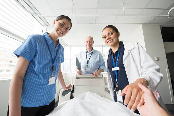 Medical team at patient's bedside, personal point of view Nurse holding patient's hand. Medical staff caring for person in hospital bed. Portrait of nurses and doctor smiling towards camera shot from point of view of the patient. POV. personal perspective stock pictures, royalty-free photos & images
