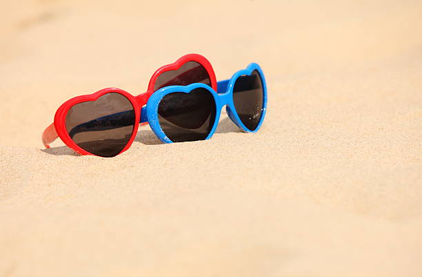 istock Colorful sunglasses shaped heart on the sand 503676325