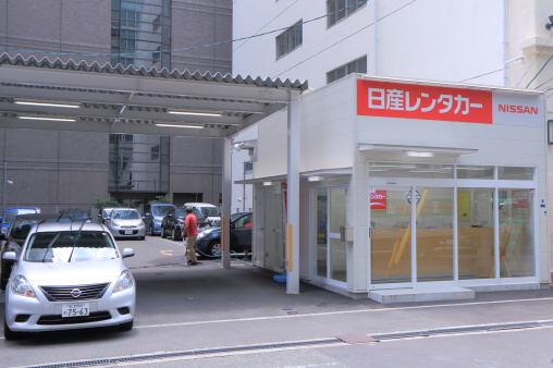 Osaka, Japan - 3 June, 2014: Store staff washes cars at Nissan Car rental office in downtown Osaka Japan.