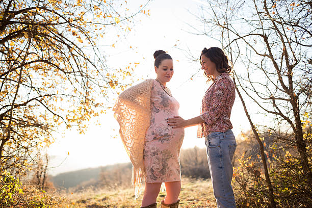 Two women touching each other,one touching belly of onother pregnant young woman