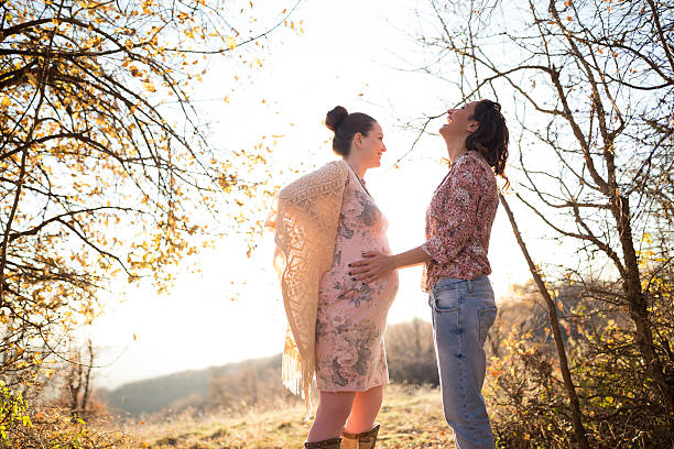 Two women touching each other,one touching belly of onother pregnant young woman
