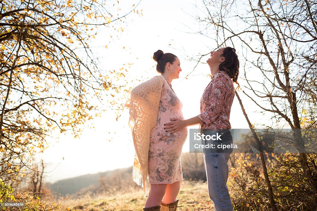 Laughing girls Two women touching each other,one touching belly of onother pregnant young woman Pregnant Stock Photo