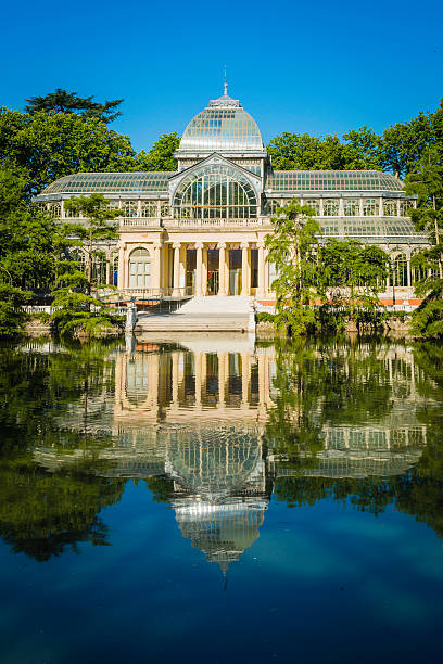 Madrid Retiro Park Palicio de Cristal reflecting tranquil lake Spain The glass and iron lattice of the 19th Century Palacio de Cristal reflecting in the tranquil waters of a lake set amongst the leafy green foliage of Buen Retiro Park in the heart of Madrid, Spain's vibrant capital city.  ProPhoto RGB profile for maximum color fidelity and gamut. palacio de cristal photos stock pictures, royalty-free photos & images