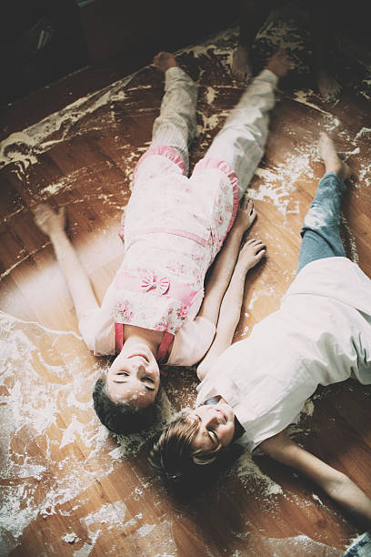 Two children lying on floor in kitchen Two children lying on floor covered with flour in kitchen flour mess stock pictures, royalty-free photos & images