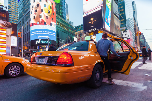 New York City, NY, USA - October 14, 2015: unidentified woman searching a taxi at Times Square in Manhattan. The Times Square is one of the worlds busiest pedestrian intersections and a major center of worlds entertainment industry