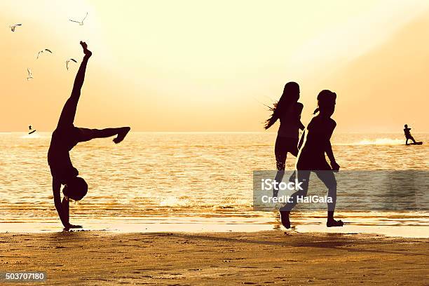 Silhouettes Of Girls On The Beach At Sunset Stock Photo - Download Image Now - Child, Teenage Girls, Breaking Wave