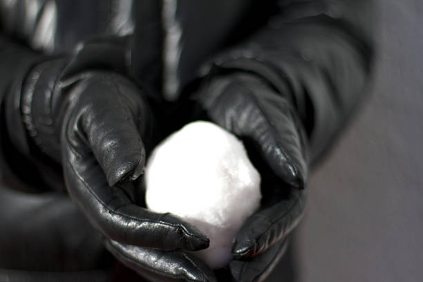 African american man holding a snowball, showing a wedding ring, playing with a friend in a snowy park during winter, enjoying fun outdoor activity and celebrating a relationship