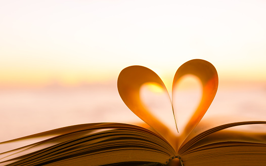 Heart from a book page against a beautiful sunset.