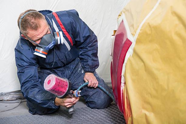 istock Body painter spraying paint on car to renew varnish 503709074
