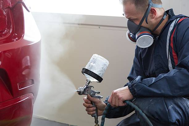 istock Body painter with airgun spraying paint on car 503709190