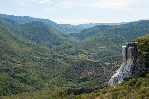 Scenic view at Hierve el Agua in Oaxaca State, Mexico. The waterfall-like rock formation on which two people are standing is created by fresh water springs, whose water is over-saturated with calcium carbonate and other minerals.