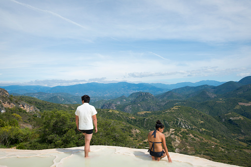Hierve el Agua, Oaxaca State, Mexico - November 3, 2014: A man and woman enjoy the water and scenic view at Hierve el Agua in Oaxaca State, Mexico. The rock formation on which the two people are located is created by fresh water springs, whose water is over-saturated with calcium carbonate and other minerals.