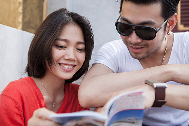 istock younger traveling man and woman reading guide book 503716856