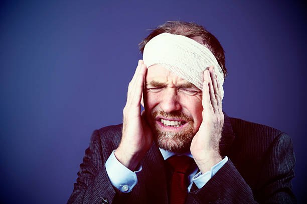 istock Businessman with bandaged head winces in pain 503725839