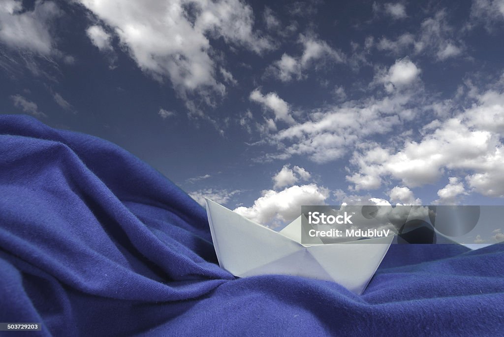 Boat in ocean. Origami boat on the canvas under blue sky with clouds. Abstract Stock Photo