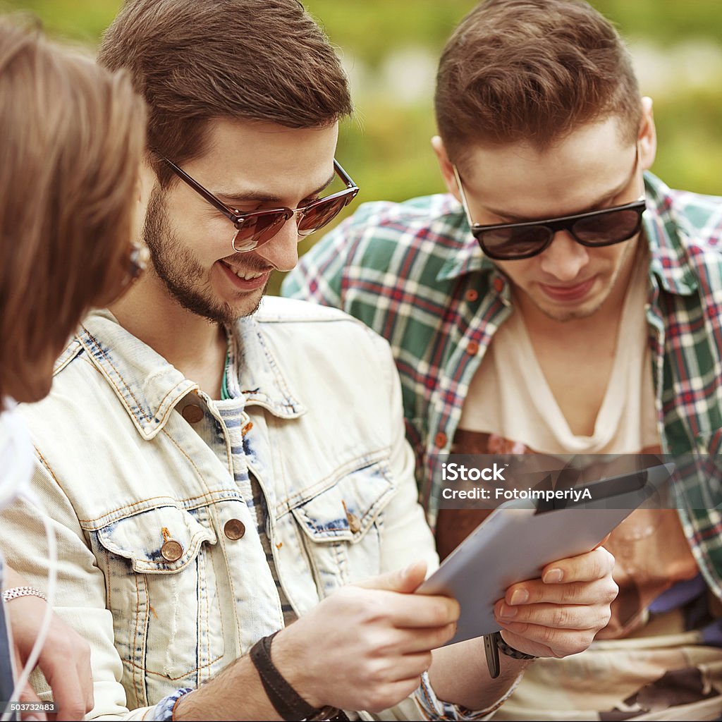 young men /friends using tablet computer in park Three young men friends using tablet computer in park Adult Stock Photo