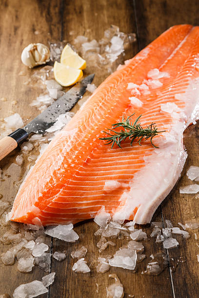 peixe salmão no gelo numa mesa de madeira - alaskan salmon imagens e fotografias de stock