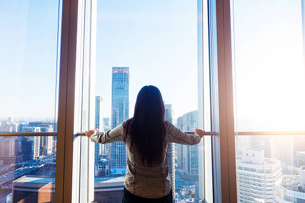istock Woman looking cityscape through window 503744038