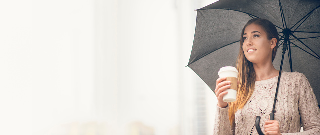 Woman holding a cup of coffee and taking a walk in the city