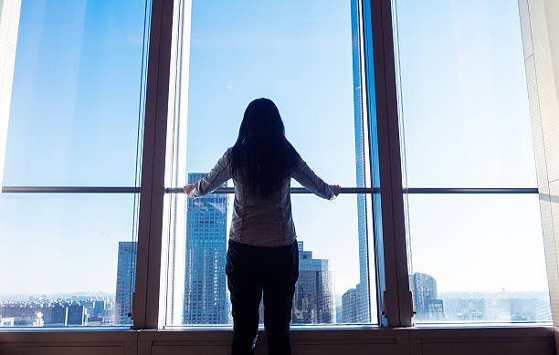 istock Woman looking cityscape through window 503752758
