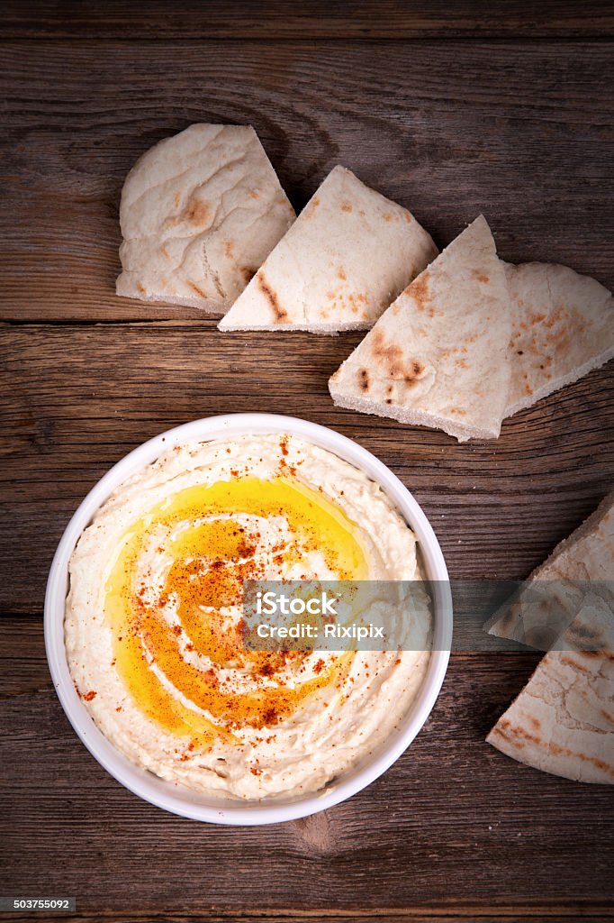 Hummus and pita bread A bowl of fresh hummus, drizzled with olive oil and paprika, served with wedges of pita bread. Appetizer Stock Photo