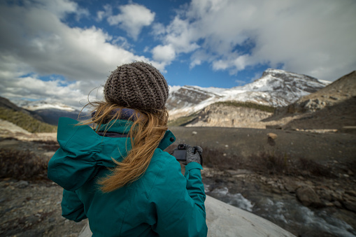 Young woman photographing the landscape with her digital camera. Bow mountains, Canada.