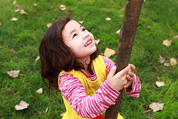 istock smiling girl holding  the tree and  looking up 503758220