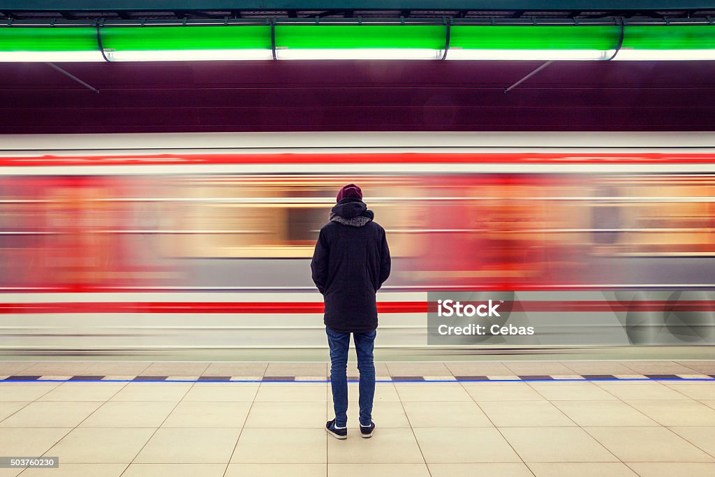 Man at subway station and moving train Lonely young man shot from behind at subway station with blurry moving train in background Train - Vehicle Stock Photo
