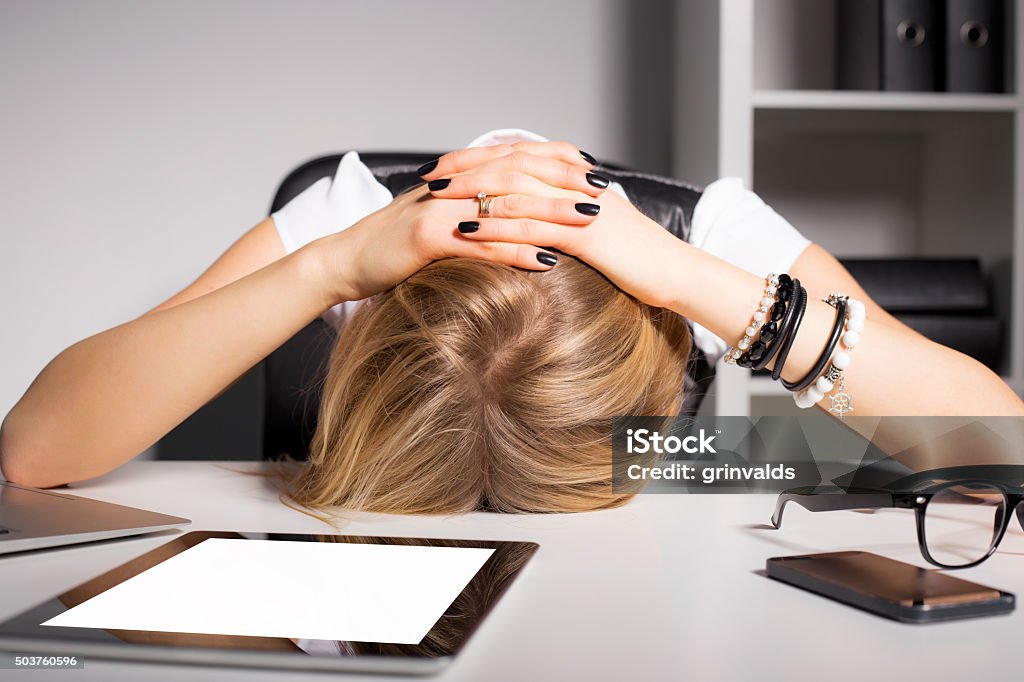 Tired business woman resting her head on desk Banging Your Head Against a Wall Stock Photo