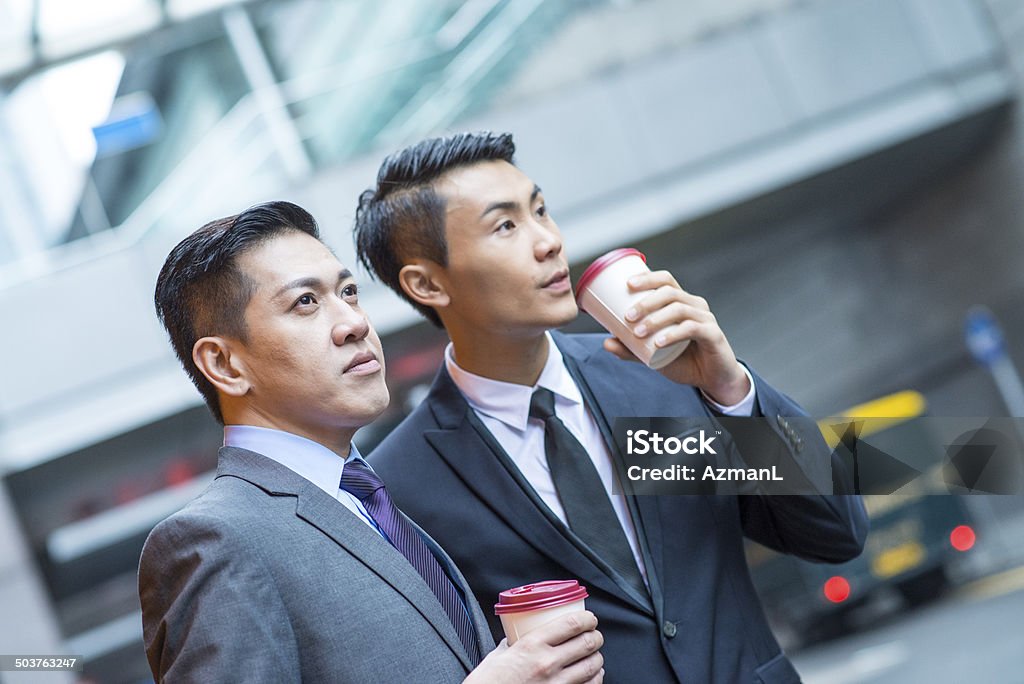 Coffee time Two asian businessman drinking coffee outdoors in the city and talking. Adult Stock Photo