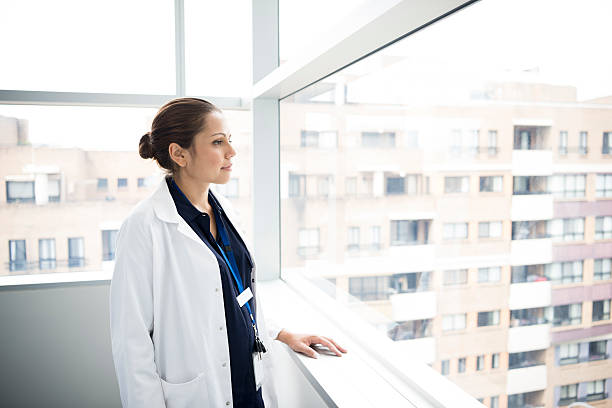 istock Junior doctor in white coat looking through hospitalwindow 503765844