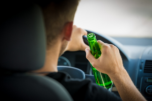 Drunk Driver Drinking Beer while Driving a Car