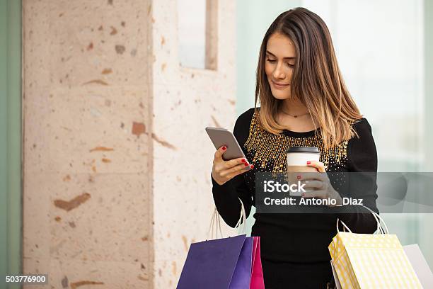 Cute Woman Using A Phone At The Shopping Mall Stock Photo - Download Image Now - 20-29 Years, Adult, Arts Culture and Entertainment