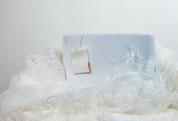 istock White mug of tea wrapped in a white scarf 503778528