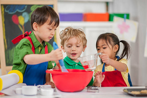 Children Baking at School A multi-ethnic group of elementary age children are baking cupcakes together at school. cooking class photos stock pictures, royalty-free photos & images