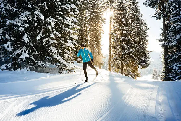 Backlit shot of a male athlete doing cross country skiing in the dolomite alps, northern Italy. Shot late in the afternoon against the sun