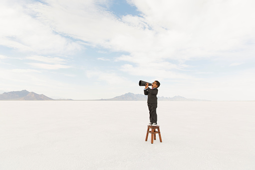 A young boy dressed in business suit yells his message through a megaphone while on the Bonneville Salt Flats of Utah. This important business message is brought to you by a very smart little businessman.